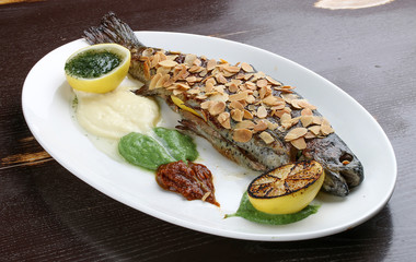 Trout with crispy almond crust and baked mashed potatoes on black background