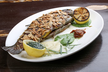 Trout with crispy almond crust and baked mashed potatoes on black background