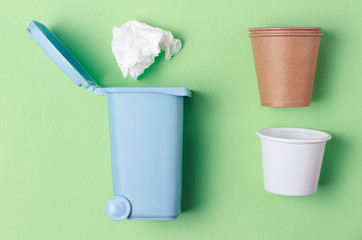 Trash can and plastic, cardboard garbage on green background, flat lay