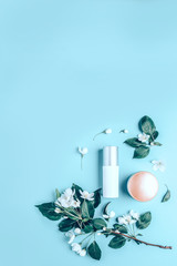 Natural organic cosmetics on blue background in a frame of flowers, blossoming apple tree.