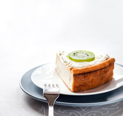 Homemade cottage cheese cake with kiwi fruit and cream on a plate