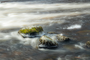 Long exposure photo. Rough river Jokelanjoki and stones in water, Kouvola, Finland.