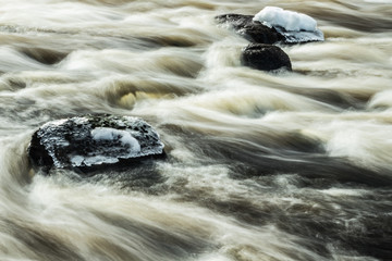 Long exposure photo. Rough river Jokelanjoki and stones in water, Kouvola, Finland.
