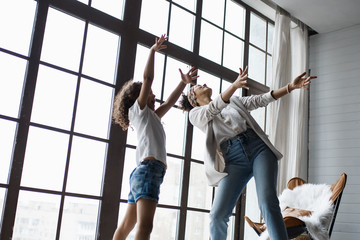 Happy loving afro american family. Young mother and her daughter playing in the nursery. Mom and daughter are dancing on the background of a large window