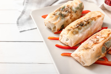 Plate with tasty fried spring rolls on table