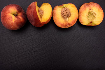 Peaches lie on a black stone slate, place for text