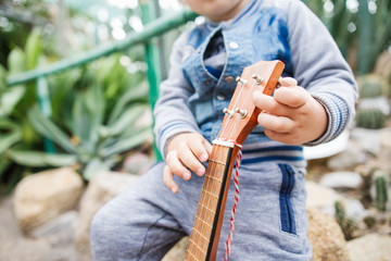 Three years blond boy holding ukulele instrument