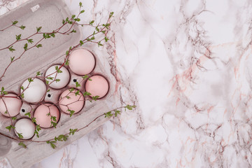 Fototapeta na wymiar Pink easter eggs on marble background. A sprig of greenery.Place for inscription. top view