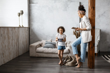 Happy loving family. Young mother and her daughter girl play in kids room. Funny mom and lovely child are having fun with tablet.