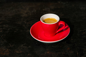 Espresso in roter Tasse auf schwarzem Tisch