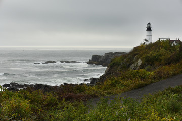 Fototapeta na wymiar Lighthouse on the wild rocky shores of the Atlantic Ocean. USA. Maine. Portland. The oldest lighthouse of America.