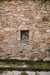 Fototapeta na wymiar vertical background of a stone wall with small window in the middle