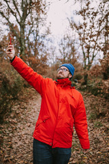 Young man in the middle of the forest raises his arm looking for coverage for his mobile phone