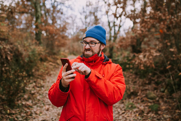 Young man fights with his mobile phone in the middle of the forest trying to make it work