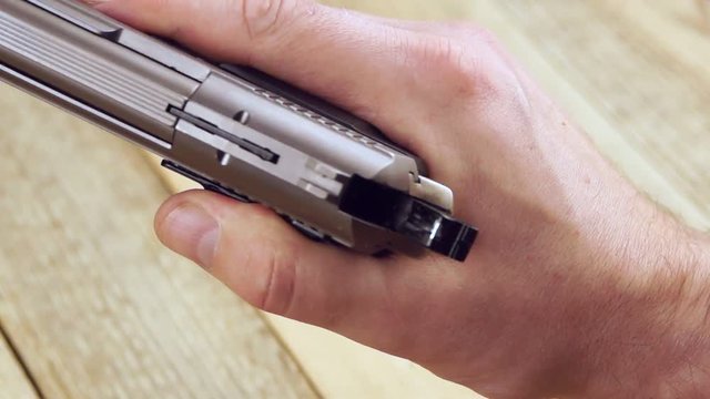Human inserts the ammunition magazine in to pistol and and charges the gun.