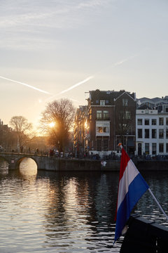 A bridge in Amsterdam with the Amstel River and a Dutch flag in the foreground.