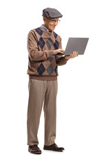 Senior man standing and using a laptop