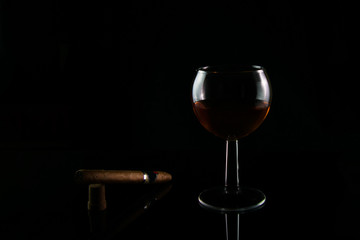 a glass of expensive cognac with a cigar