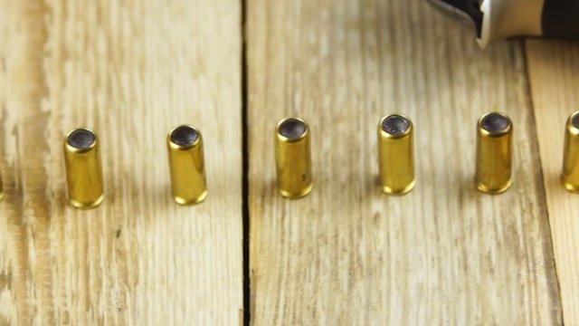 Ammunition with rubber bullets next to traumatic pistol and ammunition magazine on a wooden background