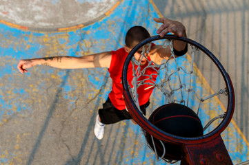 Top view of street basketball player performing power slum dunk.	