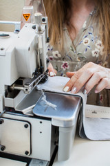Hands of a girl who sews clothes on a sewing machine. Garment factory