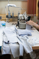 Hands of a girl who sews clothes on a sewing machine. Garment factory