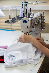 Hands of a girl who sews clothes on a sewing machine. Garment factory