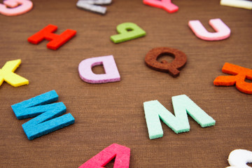 Scattered colorful alphabet letters isolated on wooden texture background. Creative concept.
