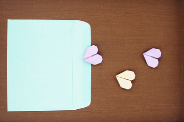 A blue envelope and an origami paper heart on a wooden texture background. Flat lay concept.