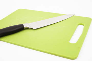 View of a knife on a green cutting board with a white background. Cooking concept.