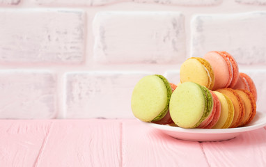 Macaroons dessert on a white plate. Pink pastel background. Top view. Copy space