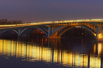 Beautiful evening view of illuminated Merto Bridge. Night city landscape. Kyiv, Ukraine