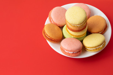 Pile of sweet and colourful french macaroons on red background