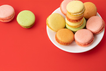 Pile of sweet and colourful french macaroons on red background