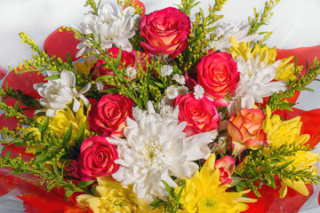 Bouquet of fresh flowers close-up. The flower arrangement is composed of miniature red roses and white and yellow chrysanthemums. flower shop, florist work. Amazing close-up bouquet of flowers.