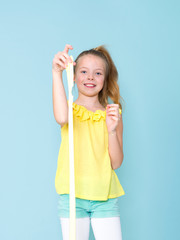 beautiful and cool and blond 9 year old girl is playing with yellow slime in front of blue background