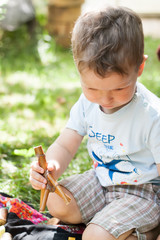 little boy plays with a wooden homemade constructor in the summer outside. Waldorf School