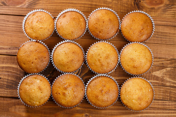 Homemade muffins in paper wrap on wooden board