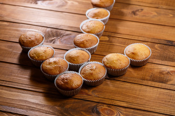 Homemade muffins in paper wrap on wooden board