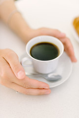 Male hand hold mug of coffee on wood table.