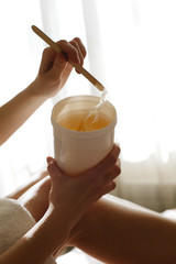 Wax depilation paste. Pasta for sugaring in a jar on a hands on white background
