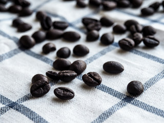 Close up roasted coffee beans on white-blue grid tablecloth. Coffee concept.
