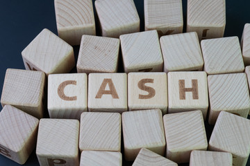 Obraz premium Cash, money or wealth asset to pay for anything concept, cube wooden block with alphabet building the word CASH at the center on dark blackboard background
