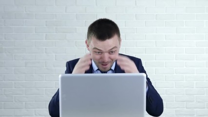 Funny young man laughing and pointing in the laptop