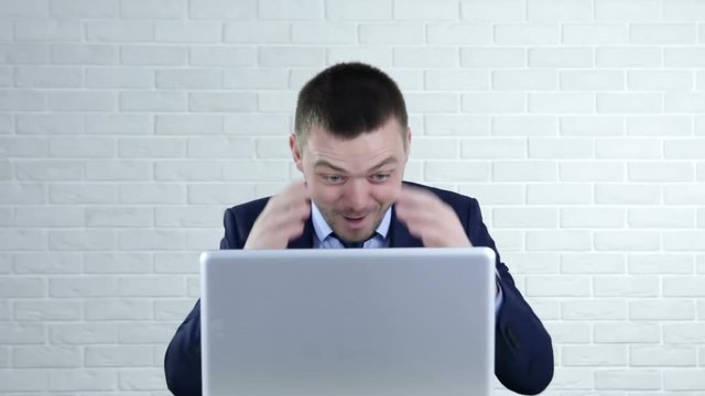 Funny young man laughing and pointing in the laptop