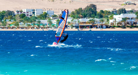 windsurfer rides on the background of the beach with a hotel and palm trees in Egypt Dahab South...