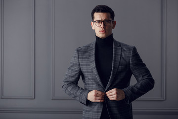 Confident,handsome man of affairs in black eyeglasses, black turtleneck and gray plaid jacket looks...