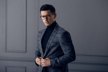 Handsome,fit man in gray suit with black turtleneck,black stylish eyeglasses looks confident at the...