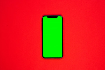 iPhone XS, smartphone, green screen on Red background top view