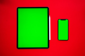 new tablet on a Red background with a keyboard and pen,  and green screen top view